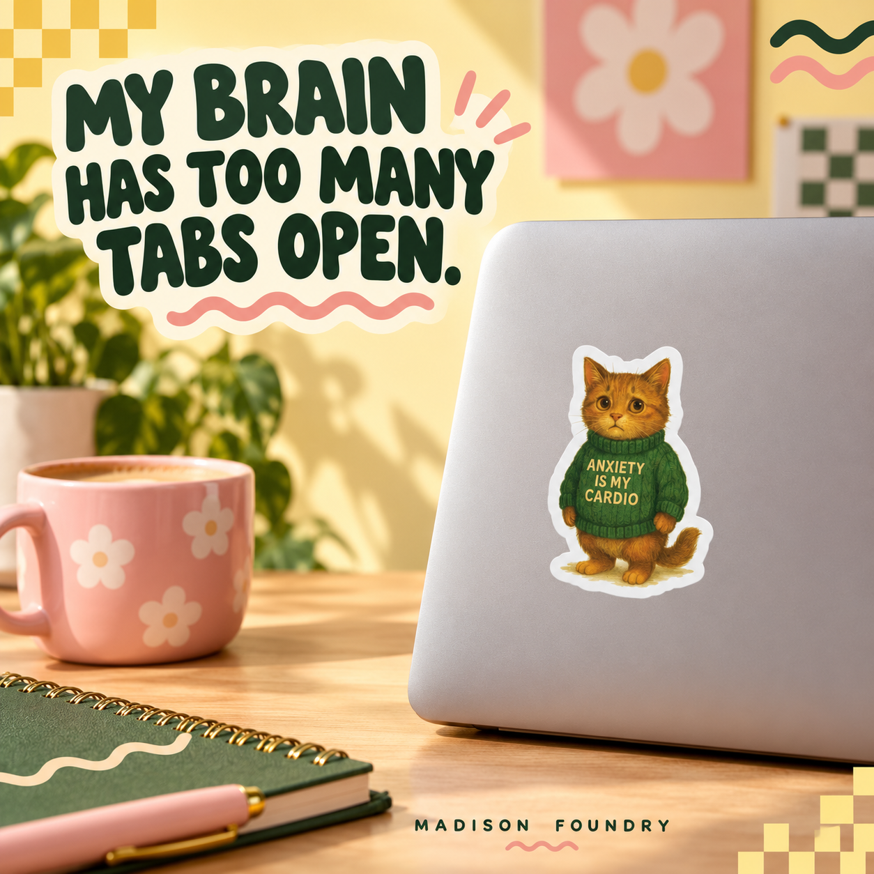 Anxiety Is My Cardio orange tabby sticker on a silver laptop in a cozy yellow workspace with pink mug and green notebook.