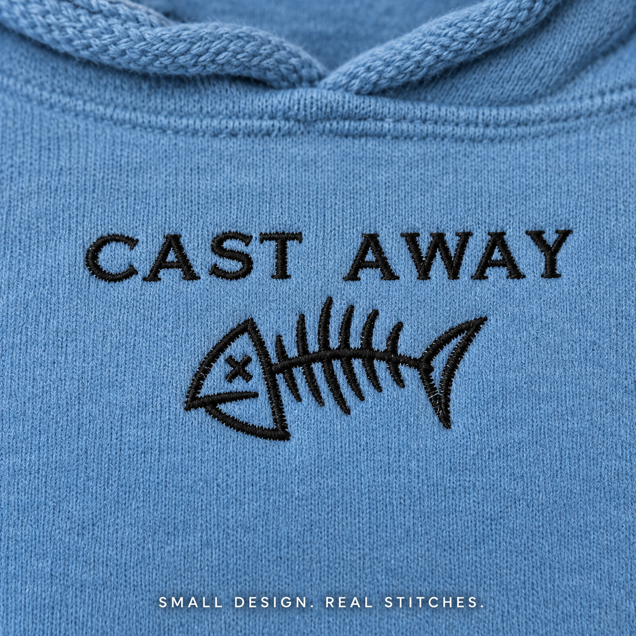 Close-up of black Cast Away lettering and fishbone embroidery on Denim blue fleece