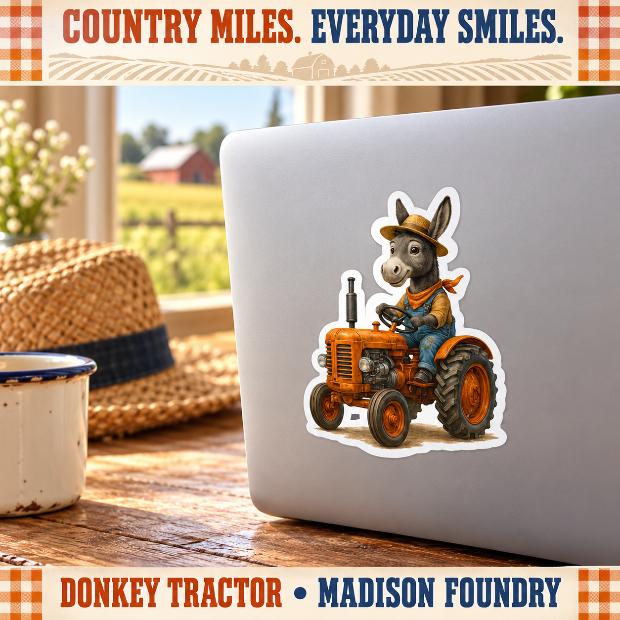 Donkey tractor sticker on a silver laptop at a sunny farmhouse desk with straw hat and enamel mug.