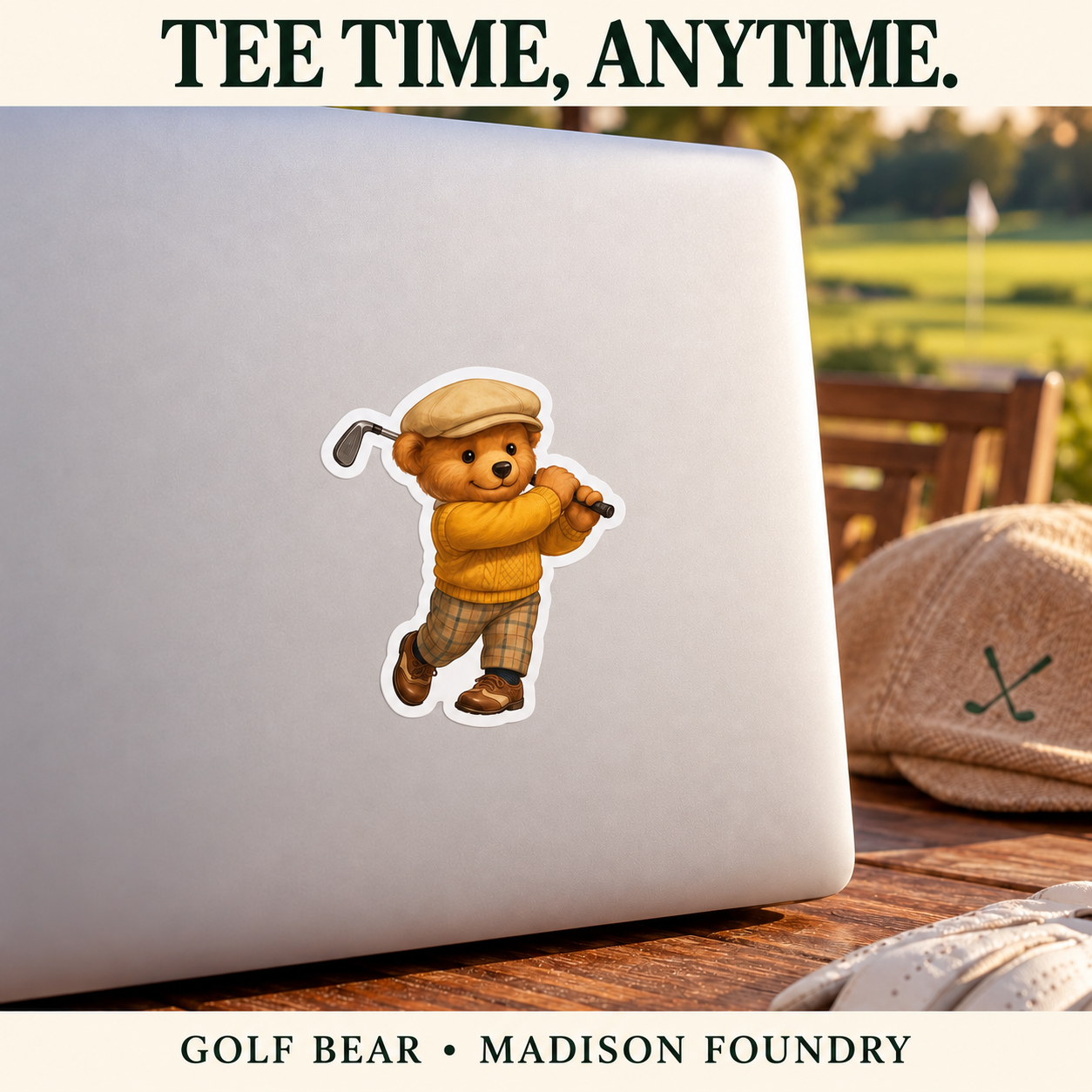 Golf Bear vinyl sticker on a plain silver laptop at a clubhouse patio table beside a golf cap and glove.
