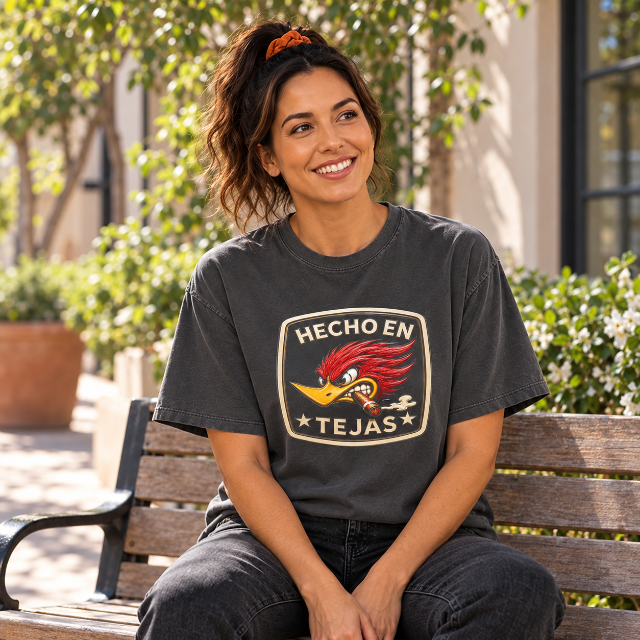 Hecho en Tejas woodpecker tee — woman relaxing on a courtyard bench