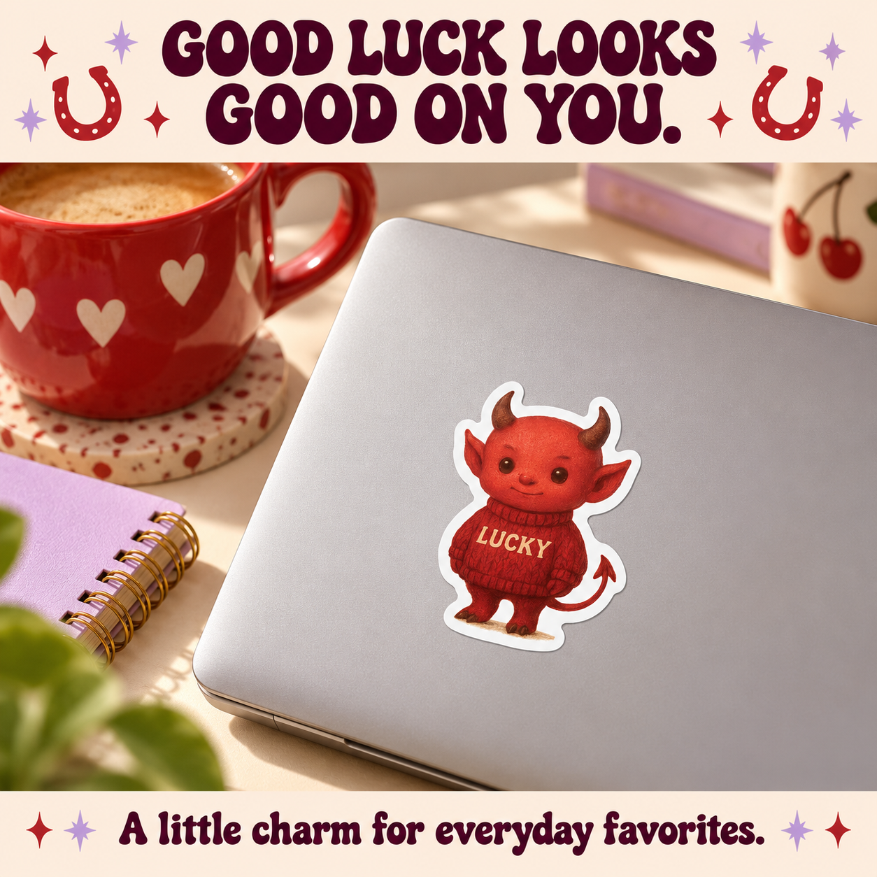 Lucky Devil vinyl sticker on a silver laptop beside a red mug and lilac notebook, with cream and plum editorial styling.