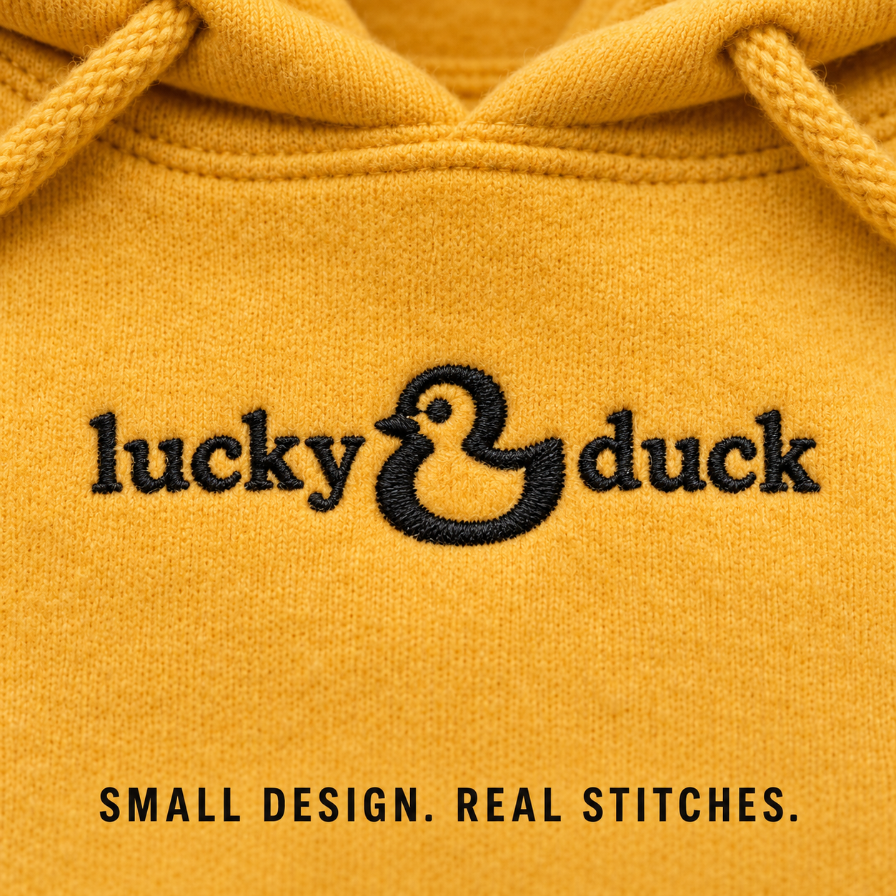 Close-up of black lucky duck embroidery stitched directly into Gold fleece