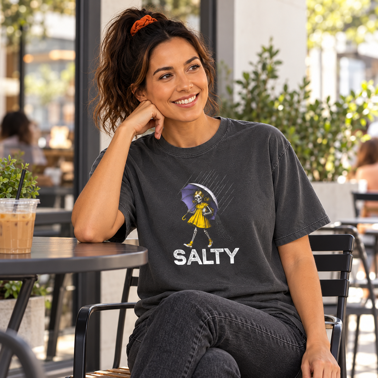 Salty Skeleton Umbrella tee — woman relaxing at an outdoor cafe