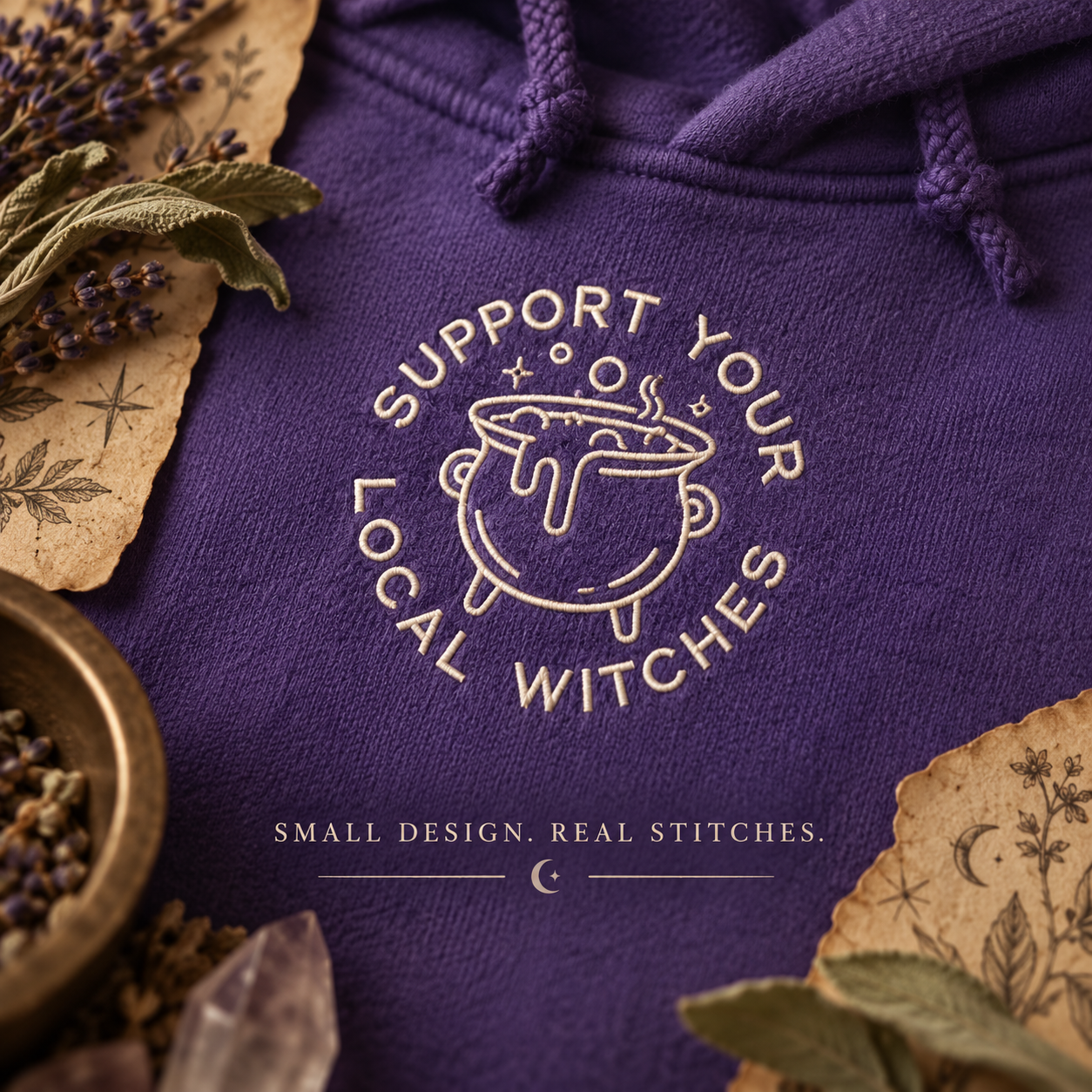 Close-up of vanilla cauldron and Support Your Local Witches embroidery on purple fleece